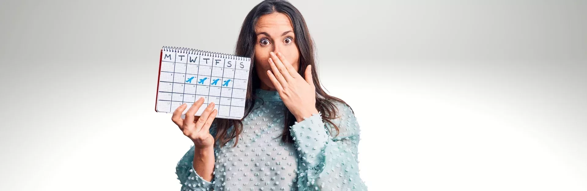 Erschrockene Frau mit Kalender in der Hand
